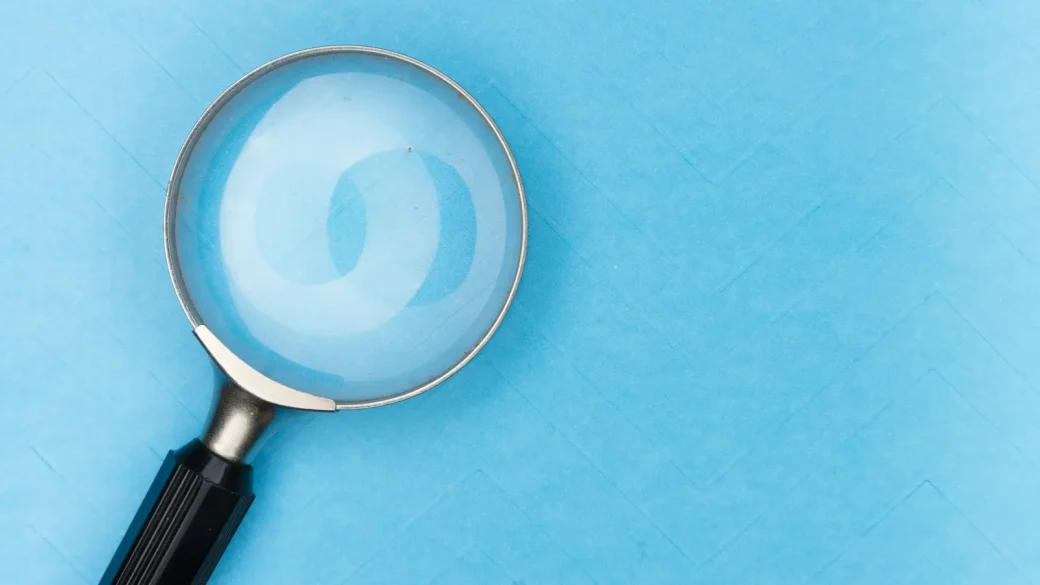 A magnifying glass held up to a laptop screen showing search results