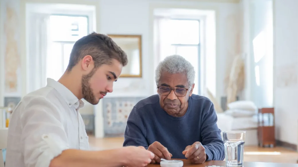 an adult child helping an older parent with a tablet at a kitchen table