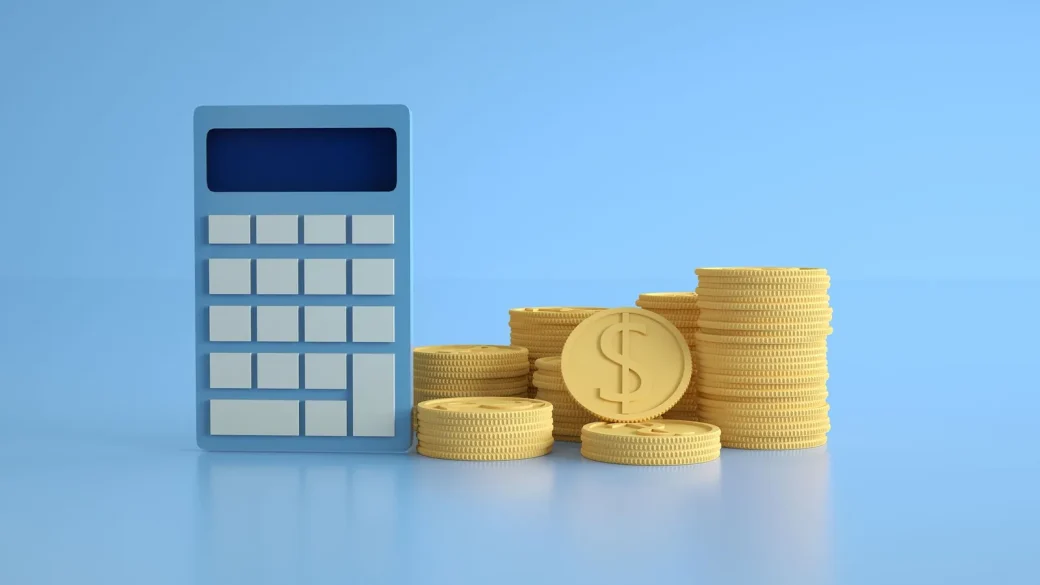 coins stacked beside a calculator on a wooden desk