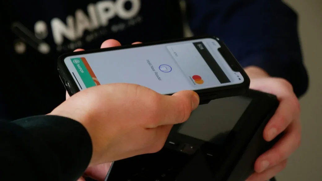 Hand tapping a phone to pay with a wallet app
