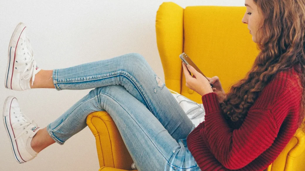 a teenager using a smartphone on a couch