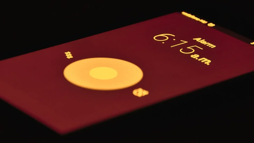 ringing alarm clock beside a phone showing an alert